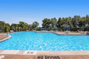 A swimming pool with a 'NO DIVING' sign, surrounded by lounge chairs and umbrellas.