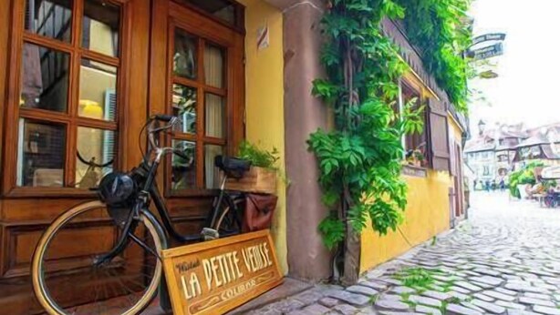 Una calle adoquinada con una bicicleta estacionada frente a un edificio que tiene un letrero que dice 'LA PETITE VERE'.