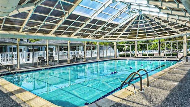 Una piscina con tetto in vetro, sedie a sdraio e vista sull'esterno.