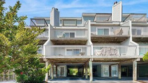 A multi-story building with balconies, a covered entrance, and a landscaped area. - Indian Harbor Villas home close to the beach with private washer/dryer & WiFi (Bethany Beach)