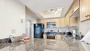 A kitchen with granite countertops, a microwave, stove, and cabinets. - Indian Harbor Villas home close to the beach with private washer/dryer & WiFi (Bethany Beach)