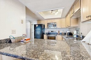 A kitchen with granite countertops, a microwave, stove, and cabinets.