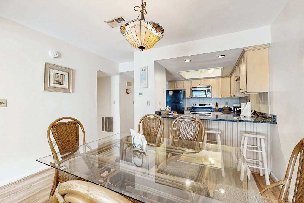 Una cocina moderna con una mesa de vidrio, sillas de mimbre y una lámpara colgante.