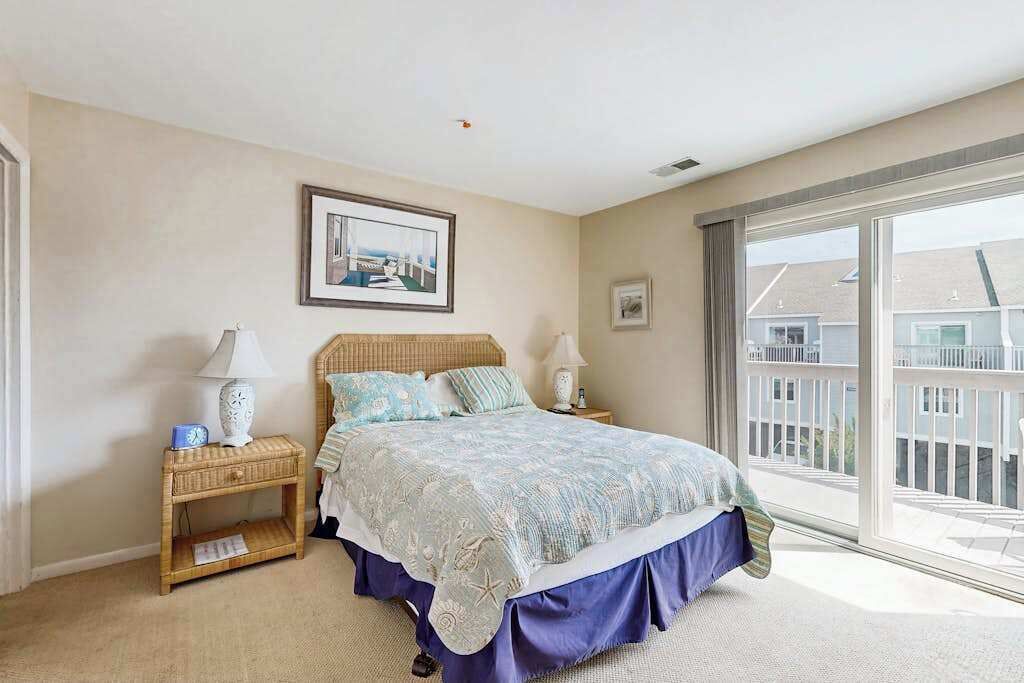A bedroom with a bed, two bedside tables, a window with a view, and a framed picture on the wall.