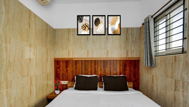 A hotel room with a wooden headboard, a bed with white and black bedding, and three framed artworks on the wall. - Saver Double Royapettah Clock Tower RKH (Chennai)
