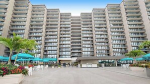 Un hotel de varios pisos con balcones, mobiliario exterior y un patio central.
