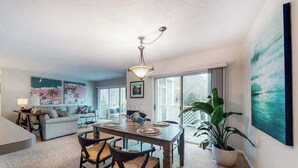 Una sala de estar moderna con comedor, ventanas grandes y vistas al exterior.