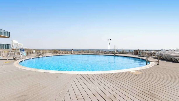 Una piscina circular sobre una terraza de madera con vistas despejadas al mar.