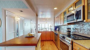 Une cuisine avec des meubles en bois, un îlot central, un four à micro-ondes et une cuisinière.