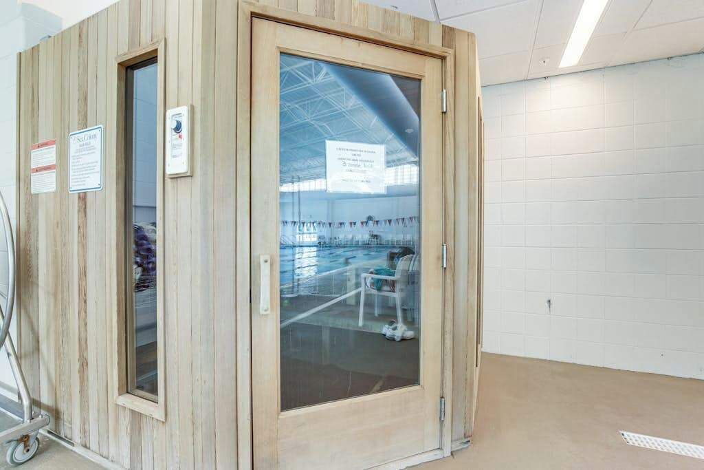 Ein Zimmer mit Holzboden und einer Glastür, ein Rollstuhl und ein Schild an der Wand.