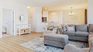 Un salon comprenant un canapé, un pouf et une console blanche agrémentée de paniers.