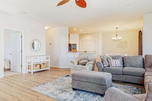 Ein Wohnzimmer mit einer Couch, einem Hocker und einem weißen Konsolentisch mit Körben.