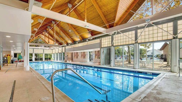 Une piscine intérieure dotée d’un plafond en bois et de grandes fenêtres.