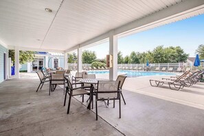 A covered outdoor area with a pool, lounge chairs, and tables. - Millville by the sea home w/ shared pool, WiFi, central AC, W/D, & gas fireplace (Millville)