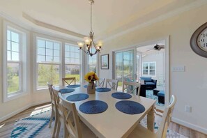 A dining area with a white table, blue placemats, and a chandelier. - Millville by the sea home w/ shared pool, WiFi, central AC, W/D, & gas fireplace (Millville)