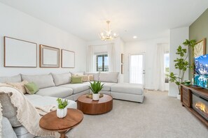 A modern living room with a sectional sofa, a round coffee table, a fireplace, and a television.