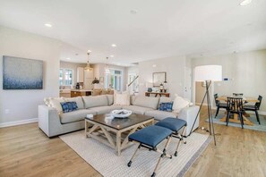 Ein geräumiges Wohnzimmer mit Ecksofa, Couchtisch und Essbereich mit Tisch und Stühlen.