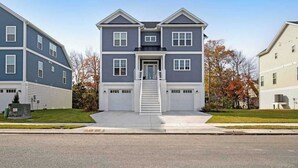 A two-story residential building with a central entrance, a front porch, and a driveway. - Luxe New Home in Tidal Walk - 2 Decks, Home Office, Dogs OK, AC & Shared Pool (Ocean View)