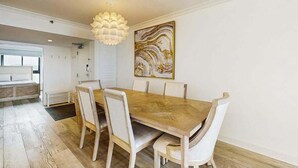 Ein Essbereich mit Holztisch, weißen Stühlen, einer Pendelleuchte und einem Bild an der Wand.