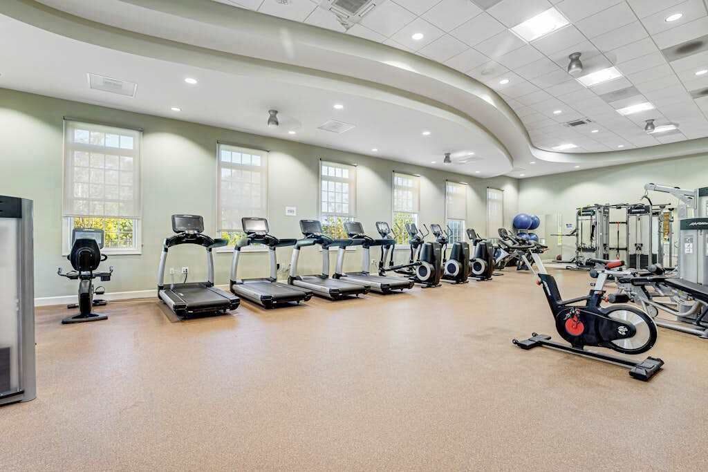Une salle de sport équipée de tapis de course, de vélos elliptiques et de matériel de musculation.