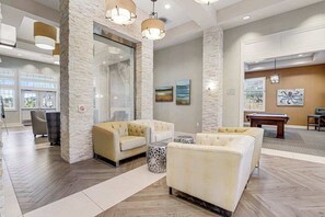 Eine Lobby mit Billardtisch, zwei Sofas, einem Couchtisch und einem Kamin.