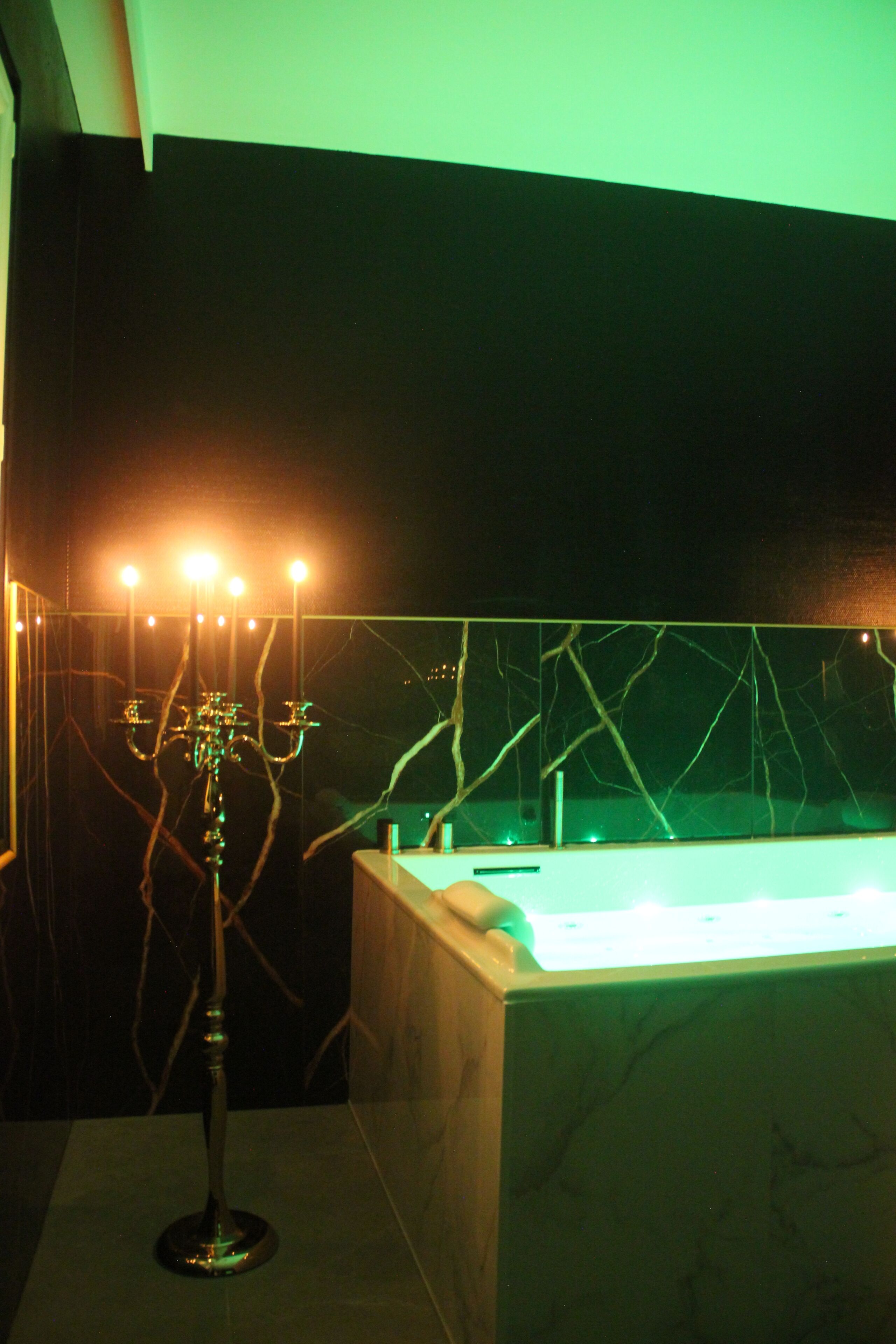 Una habitación con poca luz, una bañera, un soporte con luces y una pared con un diseño de grietas.