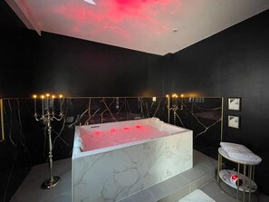 Un baño moderno con una bañera de mármol, un candelabro y un rascador para gatos.