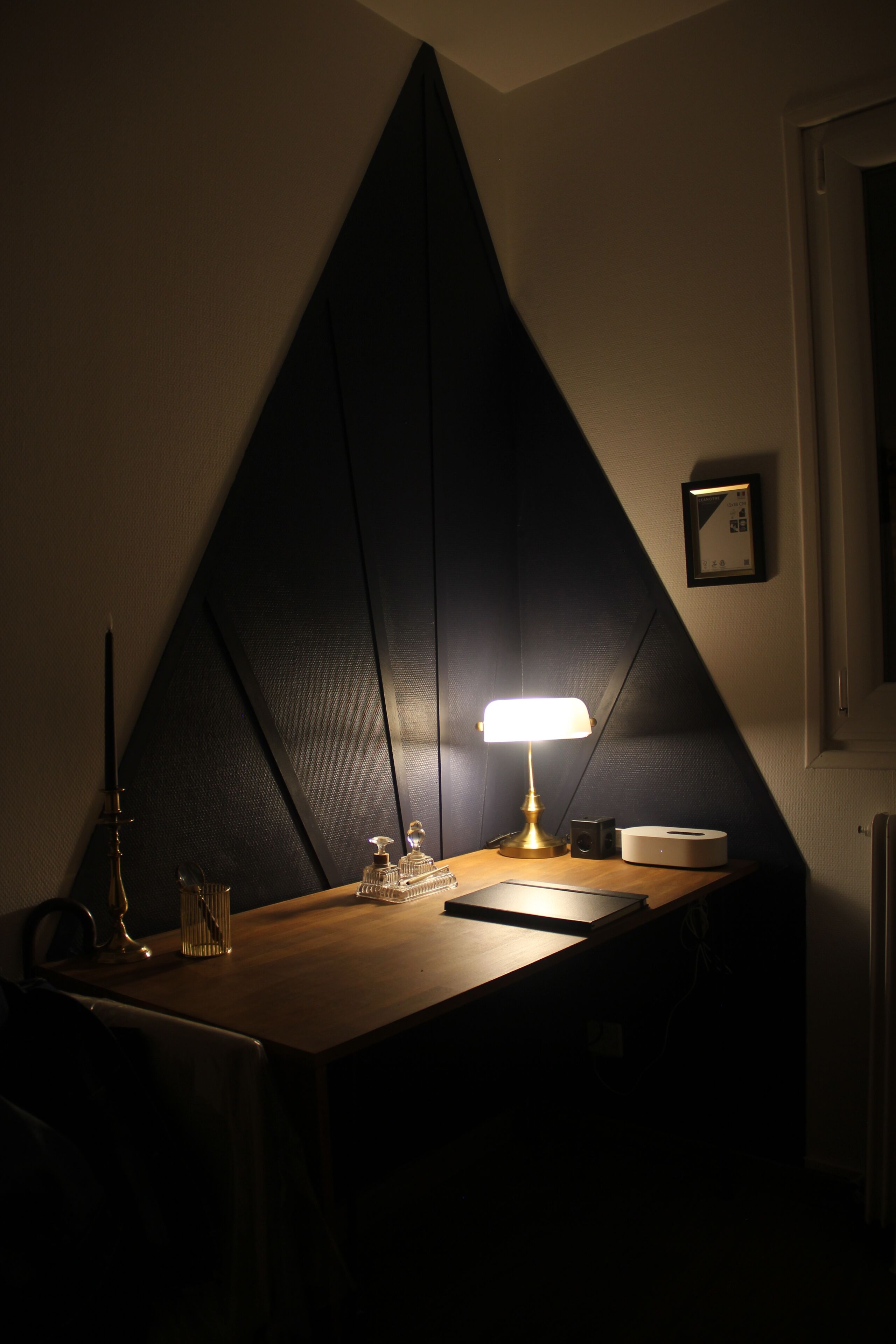 A desk with a lamp, a framed certificate, and a speaker.