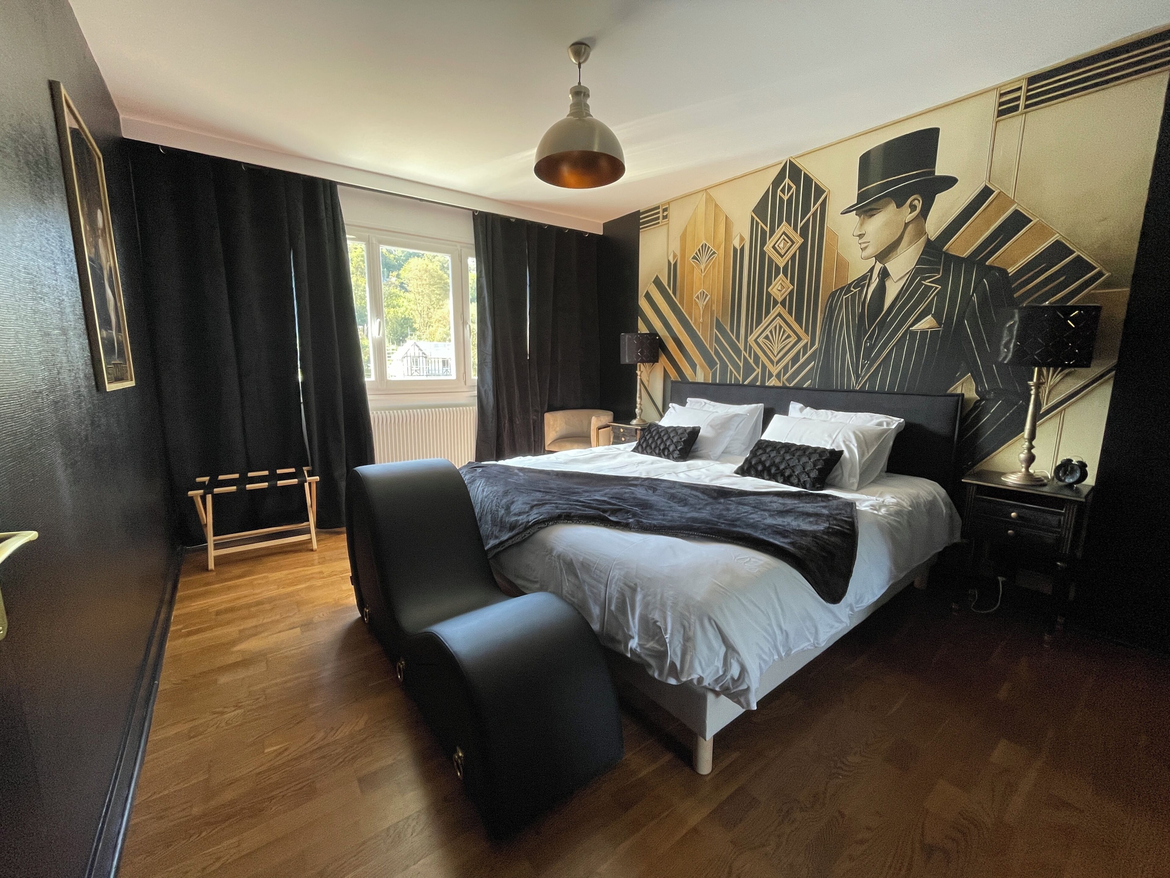 Una camera d'albergo moderna con un letto grande, un'area salotto e un murale sulla parete.
