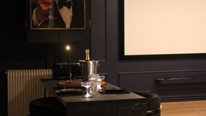 A dark-themed room with a marble table, a framed picture, and a projector screen. - Le Repaire du Gentleman - Spa, Private Cinema & King-Size Bed • Enclosed Garage (Étretat)