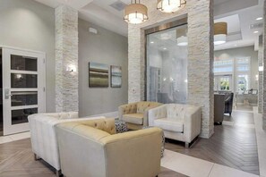Ein modernes Interieur mit einer Wand aus Naturstein, einer Sitzecke mit Sofas und einer Glaskonstruktion.