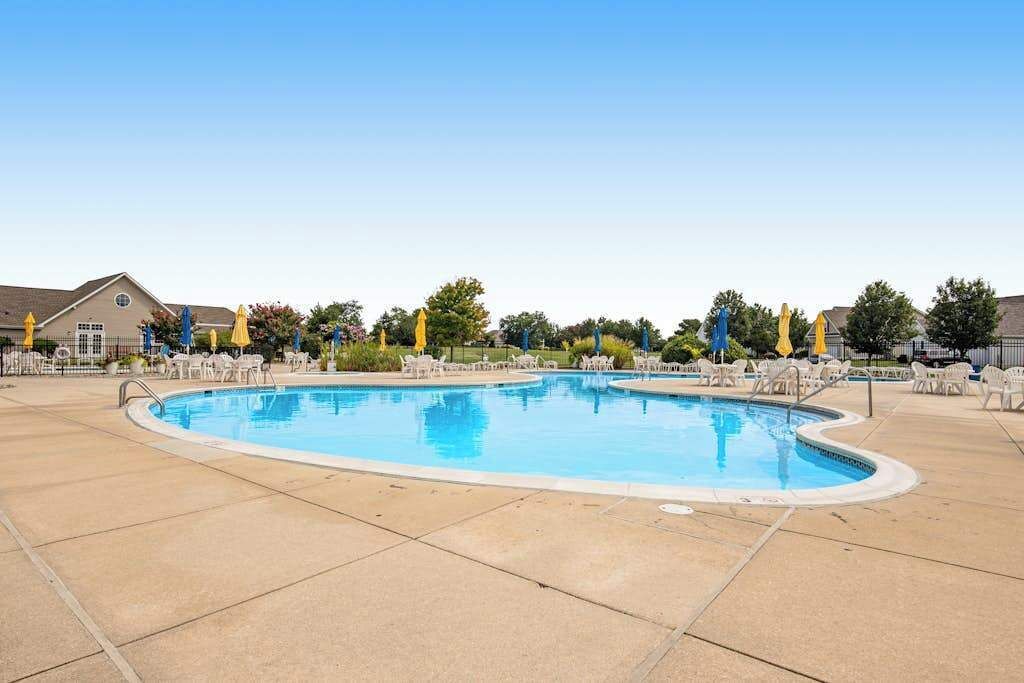 A swimming pool with lounge chairs and umbrellas, surrounded by a paved area and trees. - 2nd-floor condo at Bethany Bay with pool, on-site golf, and sports courts (Ocean View)