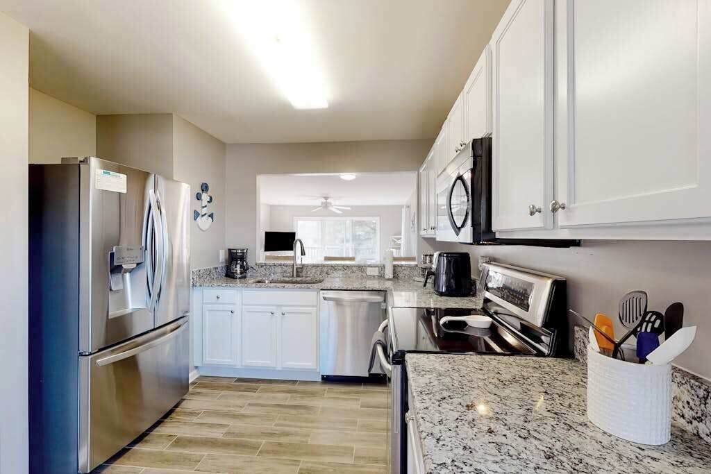 A modern kitchen with stainless steel appliances, white cabinetry, and granite countertops.