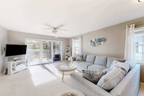 A living room with a sofa, TV, and a ceiling fan. - 2nd-floor condo at Bethany Bay with pool, on-site golf, and sports courts (Ocean View)