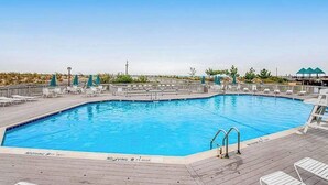 En swimmingpool med terrasse, liggestole og parasoller.