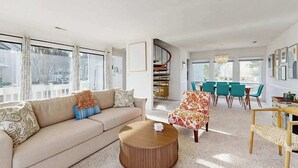 En moderne stue med sofa, sofabord og spiseområde med stole.