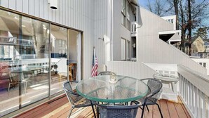 En moderne bygning med en glasbalkon, udendørs siddepladser og udsigt over det omkringliggende område.