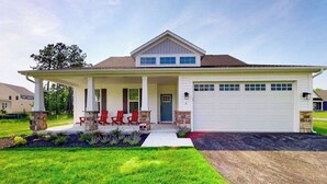 Ein eingeschossiges Haus mit Veranda, Garage und gepflegtem Rasen.