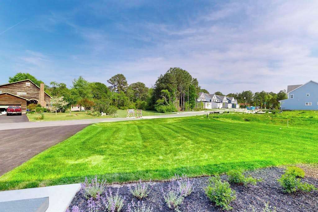 A residential area with a well-maintained lawn, a driveway, and houses with various architectural styles.