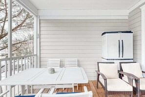 A covered patio with a white table and chairs, a wicker sofa, and a white cabinet. - Bear Trap Dunes home w/ AC, fireplace, balcony, W/D, beach shuttle (Ocean View)