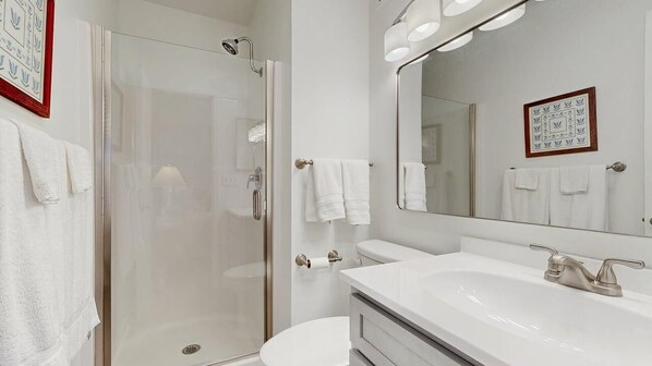 Een moderne badkamer met een douchecabine van glas, een witte wastafel en een grote spiegel.