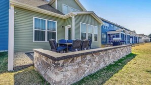 A row of single-story houses with a stone retaining wall and outdoor seating area. - Bishop's Landing townhouse with grill, outdoor pool, gym, tennis court, shuttle (Millville)