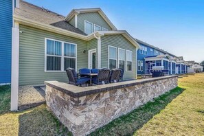 A row of single-story houses with a stone retaining wall and outdoor seating area. - Bishop's Landing townhouse with grill, outdoor pool, gym, tennis court, shuttle (Millville)