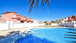 Ein Pool mit gewölbter Kante, umgeben von einem weißen Zaun und Palmen.