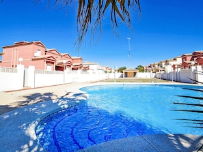 A swimming pool with a curved edge, surrounded by a white fence and palm trees. - Luz del Sol by Interhome (Calpe/Calp)