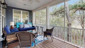 Eine überdachte Veranda mit einer Couch, Stühlen und einem Tisch.