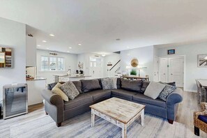 A modern living room with a sectional sofa, a coffee table, and a dining area. - The Sanctuary home near the beach with private pool, pond views, grill, porch (Bethany Beach)