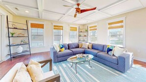 Ein Wohnzimmer mit einem Ecksofa, einem Glastisch und einem Deckenventilator.