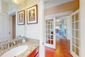 A bathroom with a granite countertop, a sink, and framed artwork on the wall. - Watermark North home near the beach with pool, fast WiFi, & washer/dryer (Bethany Beach)