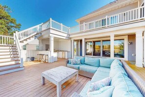Une vaste terrasse extérieure aménagée avec un canapé, une table et un escalier menant à un niveau supérieur.